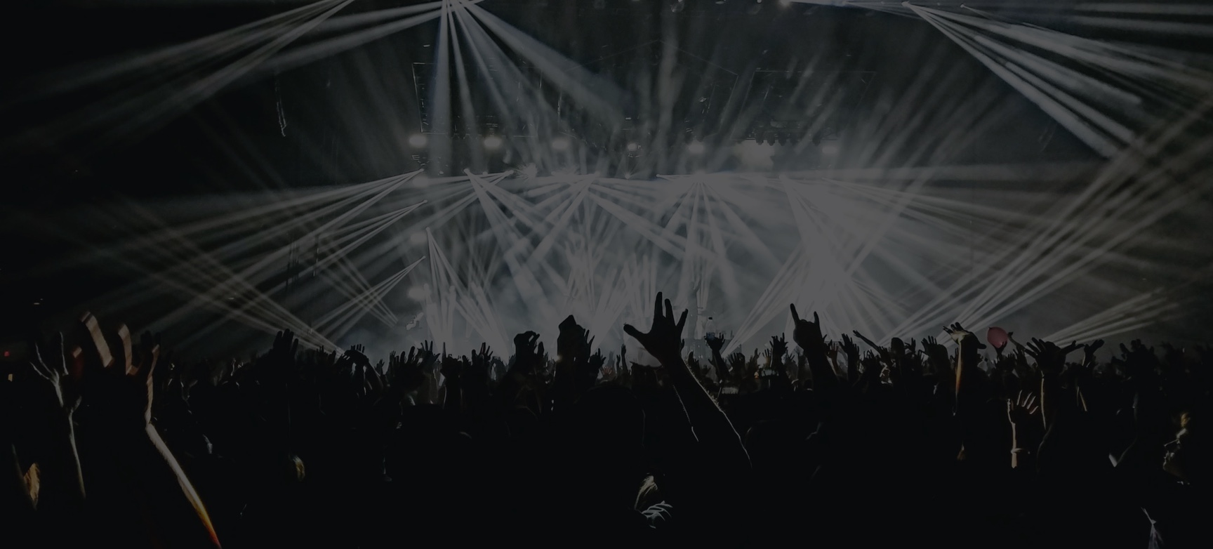 People partying at a large indoor event with lighting strobes from the stage